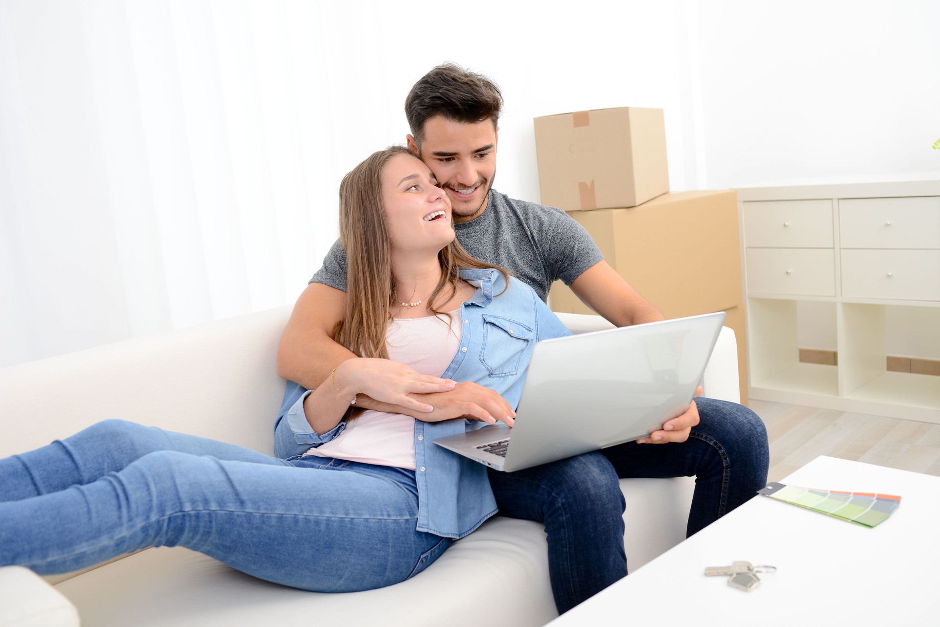 happy young couple student roommate making future project with internet computer at home while packing boxes and moving furnitures during move into their new home flat apartment